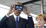 German Chancellor Angela Merkel looks on as US President Barack Obama tests VR goggles when touring the Hannover Messe, the world's largest industrial technology trade fair, in Hannover, northern Germany, Monday, April 25, 2016. (AP/Carolyn Kaster)