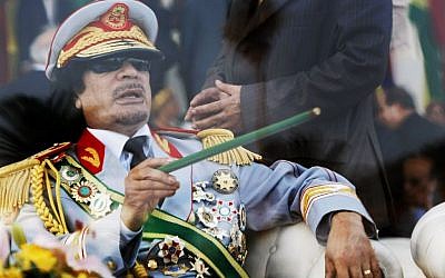 Libyan leader Moammar Gadhafi gestures with a green cane as he takes his seat behind bulletproof glass for a military parade in Green Square, Tripoli, Libya on Tuesday, Sept. 1, 2009 (AP Photo/Ben Curtis, File)