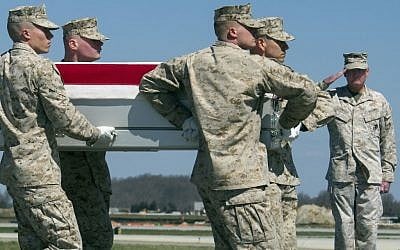 A US Marine salutes at right as soldiers unload the coffin of Marine Corp Staff Sgt. Louis Cardin on March 21, 2016, at Dover Air Force Base, Del. (AP Photo/Cliff Owen)