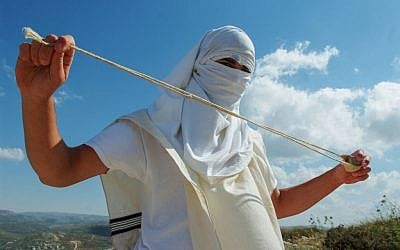 Illustrative photo of a masked Jewish settler holding a slingshot as he stands near the West Bank Jewish settlement of Mitzpeh Yitzhar, on May 19, 2013. (Mendy Hechtman/Flash90)