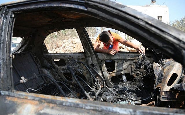Illustrative: A Palestinian boy looks at a car belonging to Palestinians, which residents said was burnt by Jewish settlers, in a village near the West Bank city of Ramallah on October 2, 2015. (Flash90) Illustrative: A Palestinian boy looks at a car belonging to Palestinians, which residents said was burnt by Jewish settlers, in a village near the West Bank city of Ramallah on October 2, 2015. (Flash90)