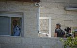 A policeman is seen in the window and family members stand on the balcony of an apartment where police are investigating a murder and suicide by a man and his wife at their home in Maaleh Adumim, April 28, 2016. (Hadas Parush/Flash90)