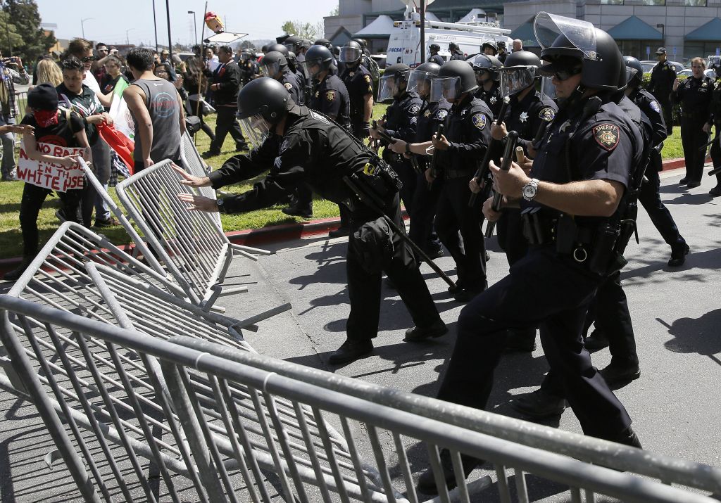 Police officers push down barricades used by a group protesting Republican presidential candidate Donald Trump outside of the Hyatt Regency hotel during the California Republican Party 2016 convention in Burlingame, Calif., Friday, April 29, 2016. (AP Photo/Eric Risberg) Police officers push down barricades used by a group protesting Republican presidential candidate Donald Trump outside of the Hyatt Regency hotel during the California Republican Party 2016 convention in Burlingame, Calif., Friday, April 29, 2016. (AP Photo/Eric Risberg)