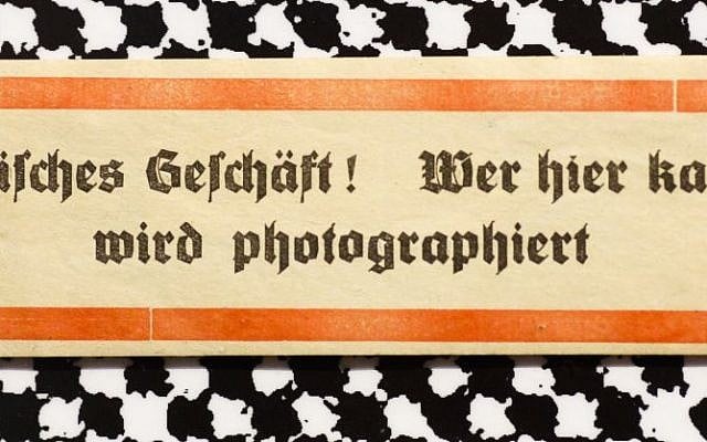A sticker from around 1938 reading: 'Jewish shop! Whoever buys here will be photographed' displayed at an exhibition of antisemitic and racist stickers at the Deutsches Historisches Museum in Berlin, Germany, April 19, 2016. (AP Photo/Markus Schreiber)