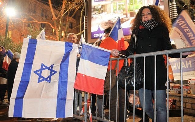 File: French Jews waving Israeli and French flags outside the Hyper Cacher a year after four Jewish shoppers were killed in a terror attack on the Paris kosher market, January 9, 2016. (Serge Attal/Flash90) File: French Jews waving Israeli and French flags outside the Hyper Cacher a year after four Jewish shoppers were killed in a terror attack on the Paris kosher market, January 9, 2016. (Serge Attal/Flash90)