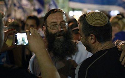 Jewish extremist activist Baruch Marzel takes a photograph with a fan during a rally in Tel Aviv on April 19, 2016 to support Elor Azria, an Israeli soldier recently charged with manslaughter after shooting a prone and wounded Palestinian assailant in the head. (Judah Ari Gross/Times of Israel)