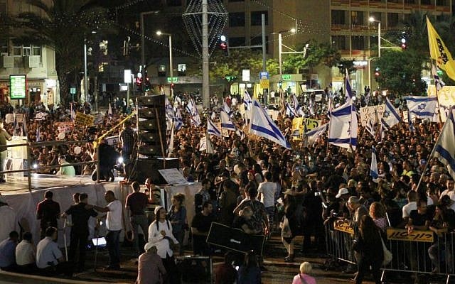 Israeli citizens hold Israeli flags and banners during a rally in Tel Aviv on April 19, 2016 to support Elor Aazria, an Israeli soldier recently charged with manslaughter after shooting a prone and wounded Palestinian assailant in the head. (Judah Ari Gross/Times of Israel)