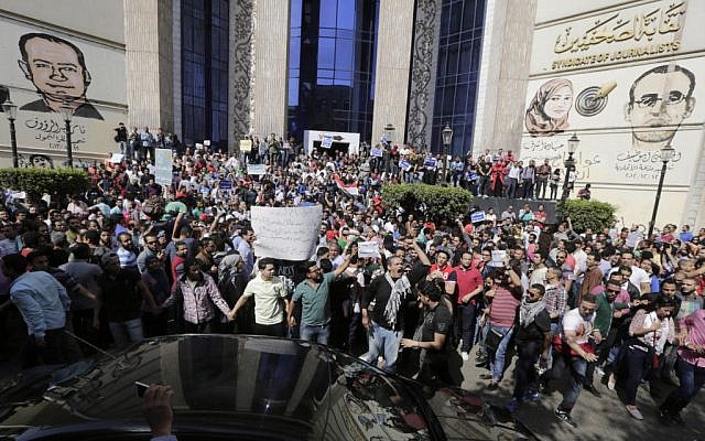 Egyptians shout slogans against Egyptian President Abdel-Fattah el-Sissi during a protest against the decision to hand over control of two strategic Red Sea islands to Saudi Arabia in front of the Press Syndicate, in Cairo, Egypt, Friday, April 15, 2016. Graffiti on the walls at background showing from left Tamer Abdel Raouf, Mayada Ashraf and Al-Housseiny Abu Daif, journalists were killed during and following 2011 uprising. (AP Photo/Amr Nabil) 
