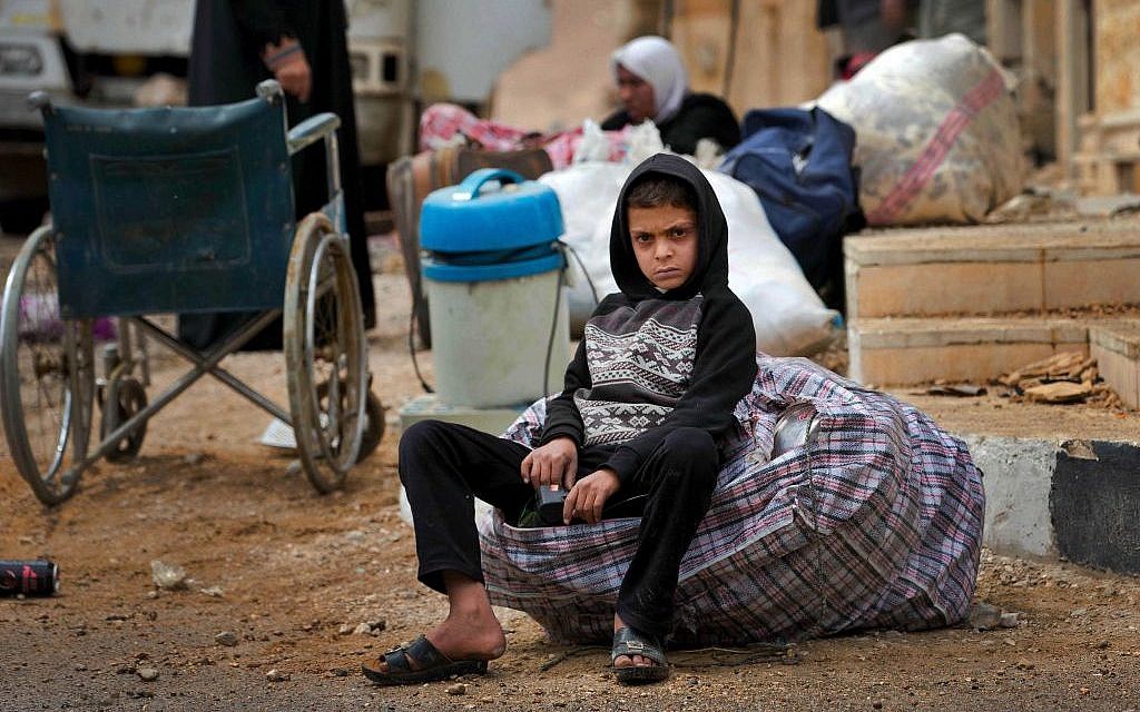In this April 14, 2016 image, a Syrian boy waits as his family loads their belongings onto a bus in the town of Palmyra in the central Homs province, Syria. (AP Photo/Hassan Ammar) In this April 14, 2016 image, a Syrian boy waits as his family loads their belongings onto a bus in the town of Palmyra in the central Homs province, Syria. (AP Photo/Hassan Ammar)