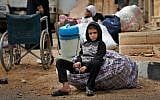 In this April 14, 2016 image, a Syrian boy waits as his family loads their belongings onto a bus in the town of Palmyra in the central Homs province, Syria. (AP Photo/Hassan Ammar)