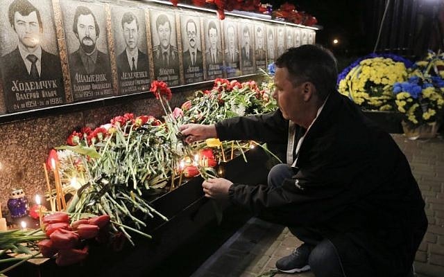 A man lays flowers to commemorate victims of the Chernobyl nuclear disaster, during a ceremony at the memorial to Chernobyl workers and firefighters in the town of Slavutych, Ukraine, early Tuesday, April 26, 2016. (AP Photo/Efrem Lukatsky)
