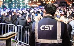 Illustrative: A Community Security Trust guard keeping watch over a Hanukkah celebration in London in 2014. (Blake Ezra Photography via JTA)