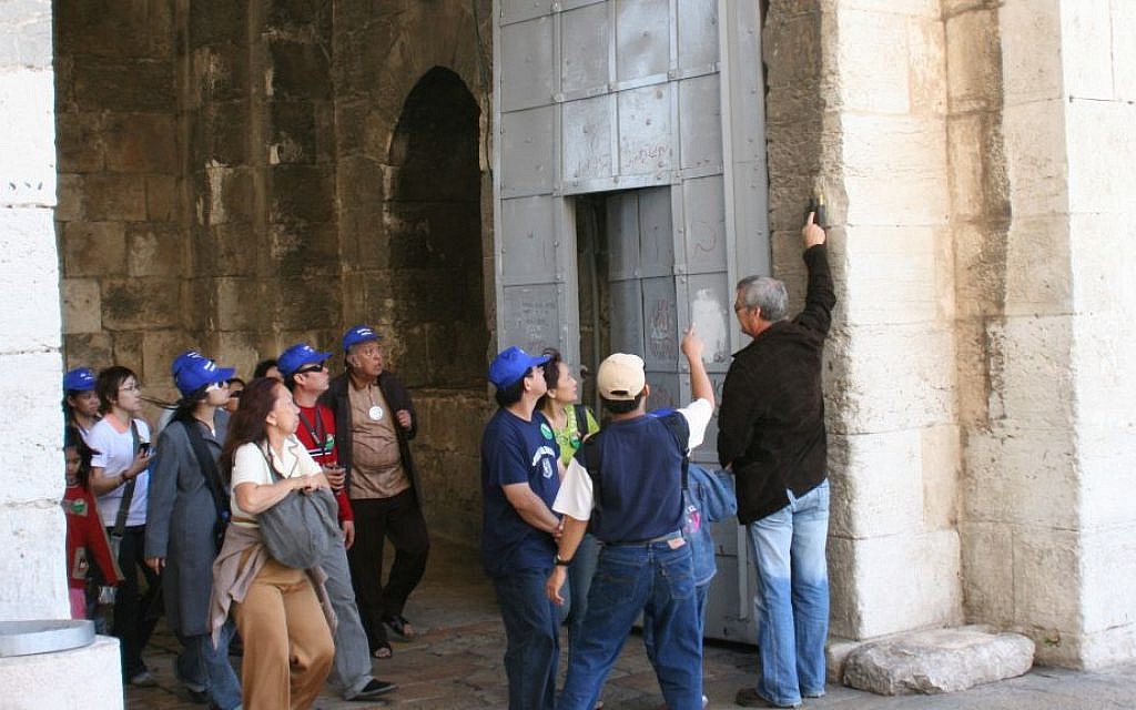 A tour group examines the mezuzah at the Old City entrance. (Shmuel Bar-Am)