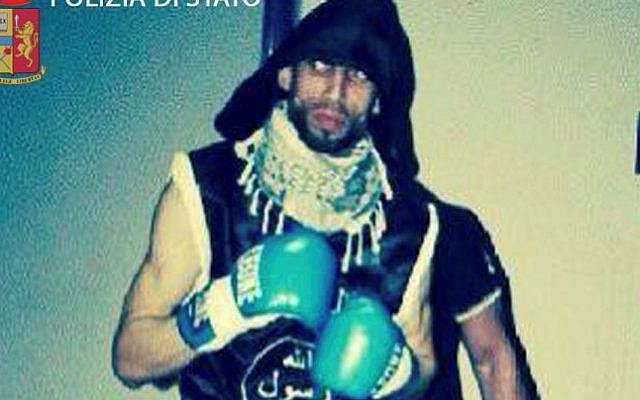 In an image released April 28, 2016, by Italian police, Moroccan-born Italian kickboxer Abderrahim Moutaharrik is seen wearing boxing gloves, shorts, a keffiyeh and a black shirt styled after the IS flag. (Italian Police)