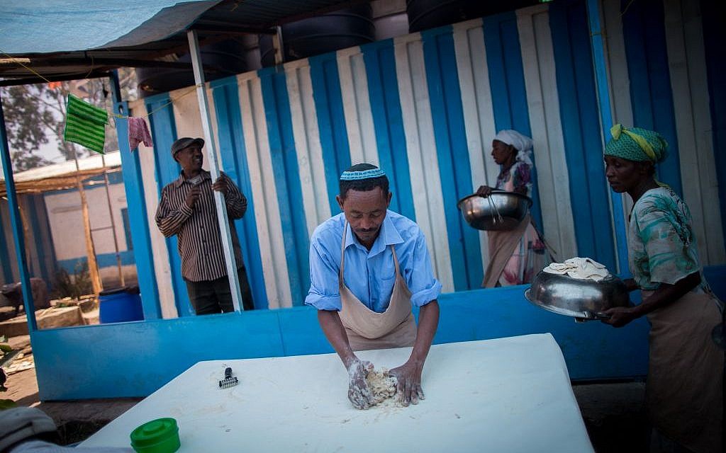 In between rounds of matzah preparation, the men of Gondar's Jewish community wipe off the tables to ensure no drop of water remains, on April 20, 2016. (Miriam Alster/Flash90)