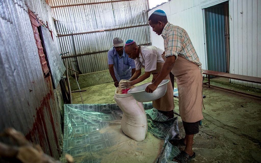 Men of Gondar's Jewish community prepare matzah before Passover on April 20, 2016. Men bring the flour for the dough from inside a synagogue classroom. (Miriam Alster/Flash90)