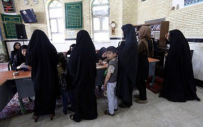 An Iranian young boy looks on as women arrive to cast their vote in the second round of parliamentary elections at a polling station in the town of Robat Karim, some 40 kms southwest of the capital Tehran, April 29, 2016. (AFP/ATTA KENARE)