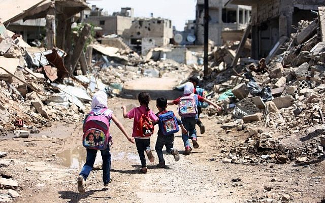 Syrian schoolchildren run past heavily damaged buildings in the rebel-held are of Jobar, on the eastern outskirts of the capital Damascus, April 30, 2016. (AFP Photo/Amer Almohibany)