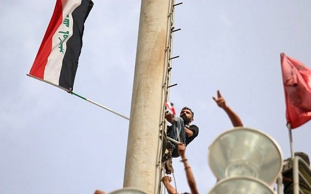 Iraqi protesters climb up a slope with their national flags in Baghdad's heavily fortified "Green Zone" on May 1, 2016. (AFP PHOTO / HAIDAR MOHAMMED ALI)