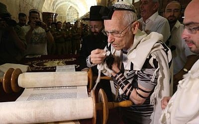 Jewish Holocaust survivors wear the tefilin, or phylacteries, and the tallit prayer shawl as they read from the Torah scrolls during their bar mitzvah ceremony, normally done at the age of 13, on May 2, 2016, at the Western Wall in Jerusalem's Old City. (AFP Photo/Menahem Kahana)