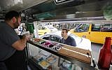 Palestinian al-Barghuti serves food to a customer at his food truck called "Food Train" which he runs with his friend al-Bibi in the West Bank city of Ramallah, May 3, 2016. (AFP/ABBAS MOMANI)