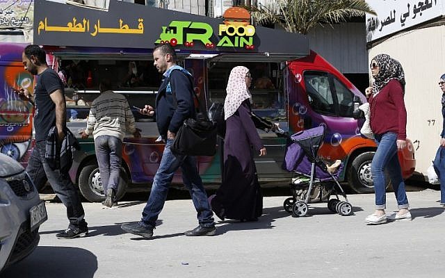 Customers walk past "Food Train", the food truck of Palestinian owners al-Barghuti and al-Bibi, in the West Bank city of Ramallah May 3, 2016. (AFP/ABBAS MOMANI)