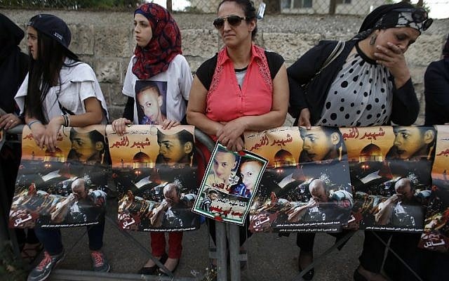 Palestinian protesters hold placards depicting portraits of Muhammed Abu Khdeir outside the Jerusalem District Court on May 3, 2016 as they await the verdict in the case of Yosef Haim Ben David, the ringleader in the killing of the Palestinian teenager last year. (AFP PHOTO / AHMAD GHARABLI)