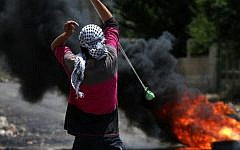 A Palestinian protester throws stones using a slingshot towards Israeli security forces during clashes on May 6, 2016.  (AFP PHOTO / JAAFAR ASHTIYEH)