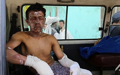 An injured Afghan man sits in an ambulance in Ghazni on May 8, 2016, following an accident on the main Kabul-Kandahar Highway. / AFP PHOTO / SAYED ZAKERIA
