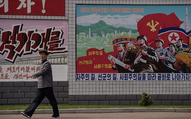 A man walks past a propaganda poster at a silk factory in Pyongyang on May 9, 2016. (AFP/ Ed Jones)