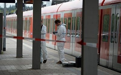 Forensic experts of the police stand next to a commuter train standig on a platform of the train station of Grafing near Munich, southern Germany, where a man killed one person and wounded three others in a knife attack on May 10, 2016. (AFP PHOTO / dpa / Andreas Gebert / Germany OUT)