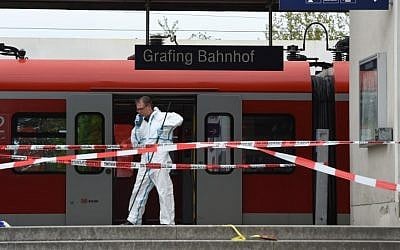 Forensic experts and policemen are seen working near the train station in Grafing, near Munich, southern Germany, where a man killed one person and wounded three others in a knife attack on May 10, 2016. (AFP PHOTO / Christof Stache)