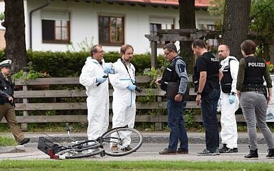 Forensic experts and policemen are seen working near the train station in Grafing, near Munich, southern Germany, where a man killed one person and wounded three others in a knife attack on May 10, 2016. (AFP PHOTO / Christof Stache)