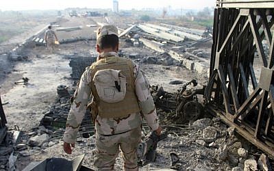 Fighters from Iraqi pro-government forces inspect the damage at the Albu Aitha bridge north of Ramadi following an attack a military source said was carried out by the Islamic State (IS) group, May 12, 2016. (Moadh Al-Dulaimi/AFP)