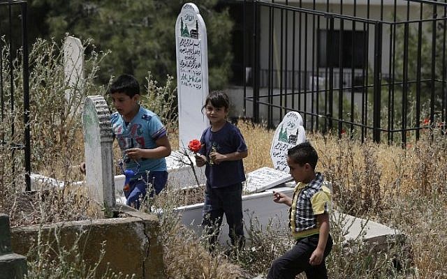 Children place flowers on a tomb in the old cemetery of Bar Elias in Lebanon's Bekaa Valley on May 13, 2016. (AFP PHOTO / JOSEPH EID) Children place flowers on a tomb in the old cemetery of Bar Elias in Lebanon's Bekaa Valley on May 13, 2016. (AFP PHOTO / JOSEPH EID)