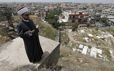 Lebanese Sunni Cleric Mohammed al-Nouz recites al-Fatiha (the first chapter of the Koran) over graves of the old cemetery of Bar Elias in Lebanon's Bekaa Valley on May 13, 2016. (AFP PHOTO / JOSEPH EID)