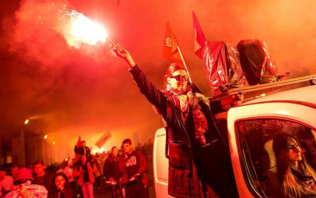 Protesters light flares and wave flags while marching through a street during an anti-government protest in Skopje, Macedonia, on May 16, 2016. (Robert Atanasovski/AFP)