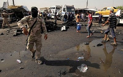 Iraqi soldiers and civilians check the damage after a suicide bomber detonated an explosives-rigged vehicle in northern Baghdad's Sadr City, May 17, 2016. (AFP/AHMAD AL-RUBAYE)