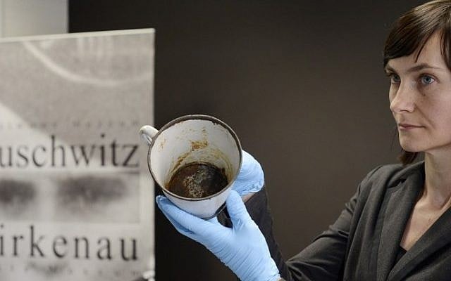 A woman presents on May 19, 2016 a metal mug with a double bottom in which a gold ring and necklace were found by employees of the Auschwitz-Birkenau museum in Oswiecim, Poland., one of thousands of pieces of kitchenware now on display at the museum. (Bartosz Siedlik/AFP)