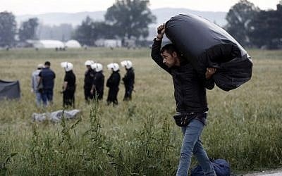 A refugee man carries his belongings during an evacuation operation by police forces of a makeshift migrant camp at the border at the Greek-Macedonian border near the village of Idomeni, on May 24, 2016. (AFP PHOTO / POOL / Yannis KOLESIDIS)
