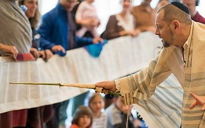 Rabbi Amichai Lau-Lavie chants as members of the Lab/Shul community hold an unfurled Torah scroll. (Courtesy)
