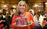 Marian Harper, owner of the Carnegie Deli, holds an overstuffed Pastrami sandwich (courtesy: Carnegie Deli)