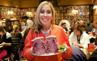 Marian Harper, owner of the Carnegie Deli, holds an overstuffed Pastrami sandwich (courtesy: Carnegie Deli)