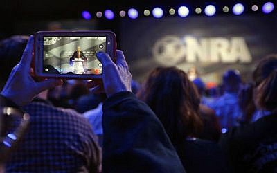A National Rifle Association attendee photographs Republican presidential candidate Donald Trump as he speaks at the NRA convention, Friday, May 20, 2016, in Louisville, Ky. (AP Photo/Mark Humphrey)