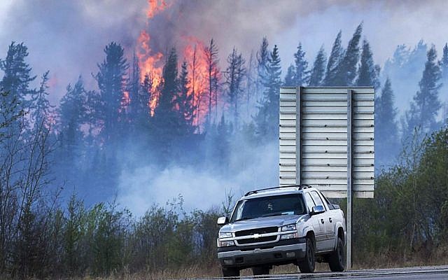 Flames flare up from hotspots from a wildfire along a highway to Fort McMurray, Alberta, Canada, Sunday, May 8, 2016. (Ryan Remiorz/The Canadian Press via AP)