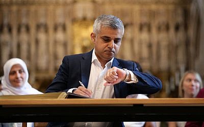 London's new mayor, Sadiq Khan, looks at his watch during the official signing ceremony in Southwark Cathedral, London, Saturday May 7, 2016. (Yui Mok/Pool via AP)