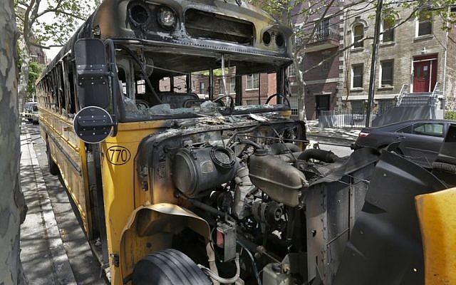 The remains of a school bus that was burned Sunday May 8, 2016, sits on a street in the Crown Heights section of the Brooklyn borough of New York, Wednesday May 11, 2016. (AP/Richard Drew)