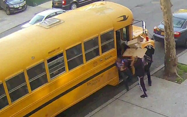 In this frame grab taken from surveillance video, children place pieces of cardboard on a school bus before lighting it on fire, Sunday, May 8, 2016, in the Crown Heights section of the Brooklyn borough of New York. (Beth Rifkah School via AP)