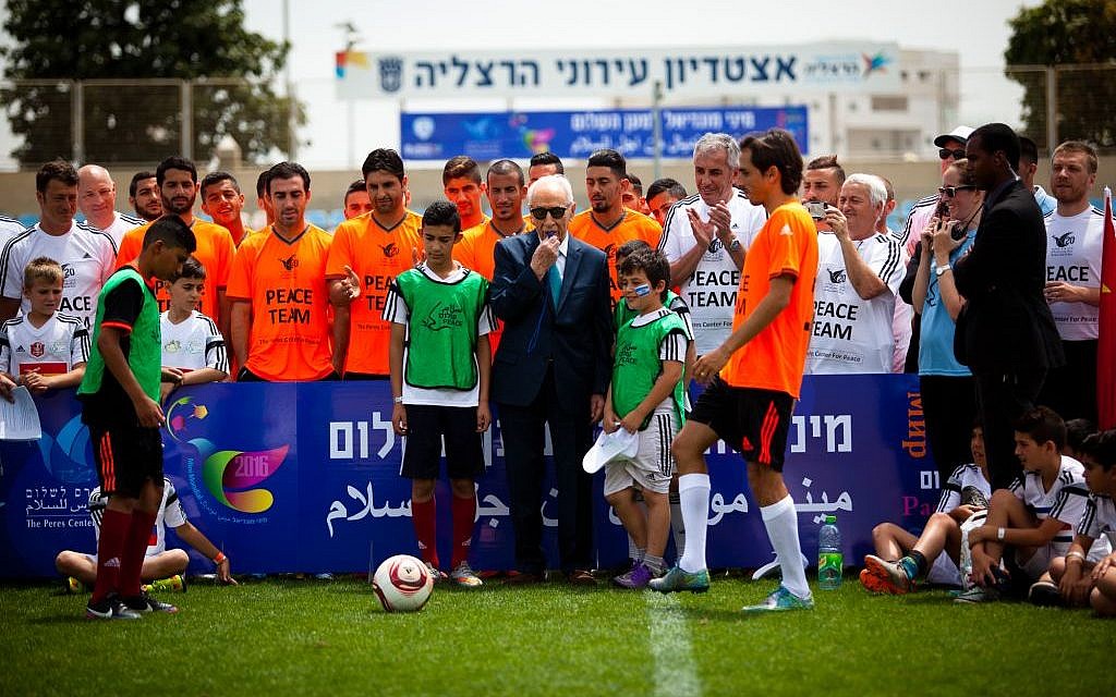 Shimon Peres, in suit, with soccer players and future soccer players at the Peres Center For Peace's Mini Mondial for Peace in Herzliya on May 9, 2016. (Efrat Saar/Courtesy)