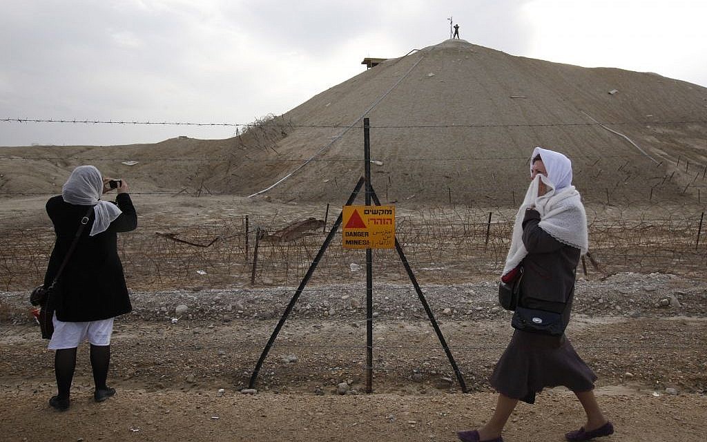 Greek Orthodox Christian pilgrims walk by a sign warning of mines as they take part in a traditional Epiphany baptism ceremony, at Qasr el Yahud on January 18, 2011. (Miriam Alster/Flash90) Greek Orthodox Christian pilgrims walk by a sign warning of mines as they take part in a traditional Epiphany baptism ceremony, at Qasr el Yahud on January 18, 2011. (Miriam Alster/Flash90)